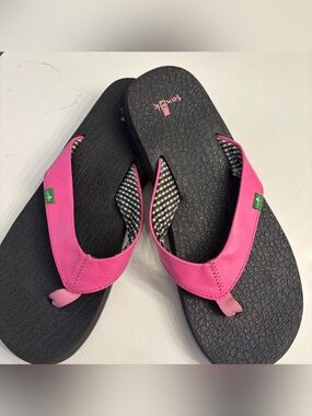 Classic black Sanuk flip flops. Striped fabric on the straps with pink strap.
